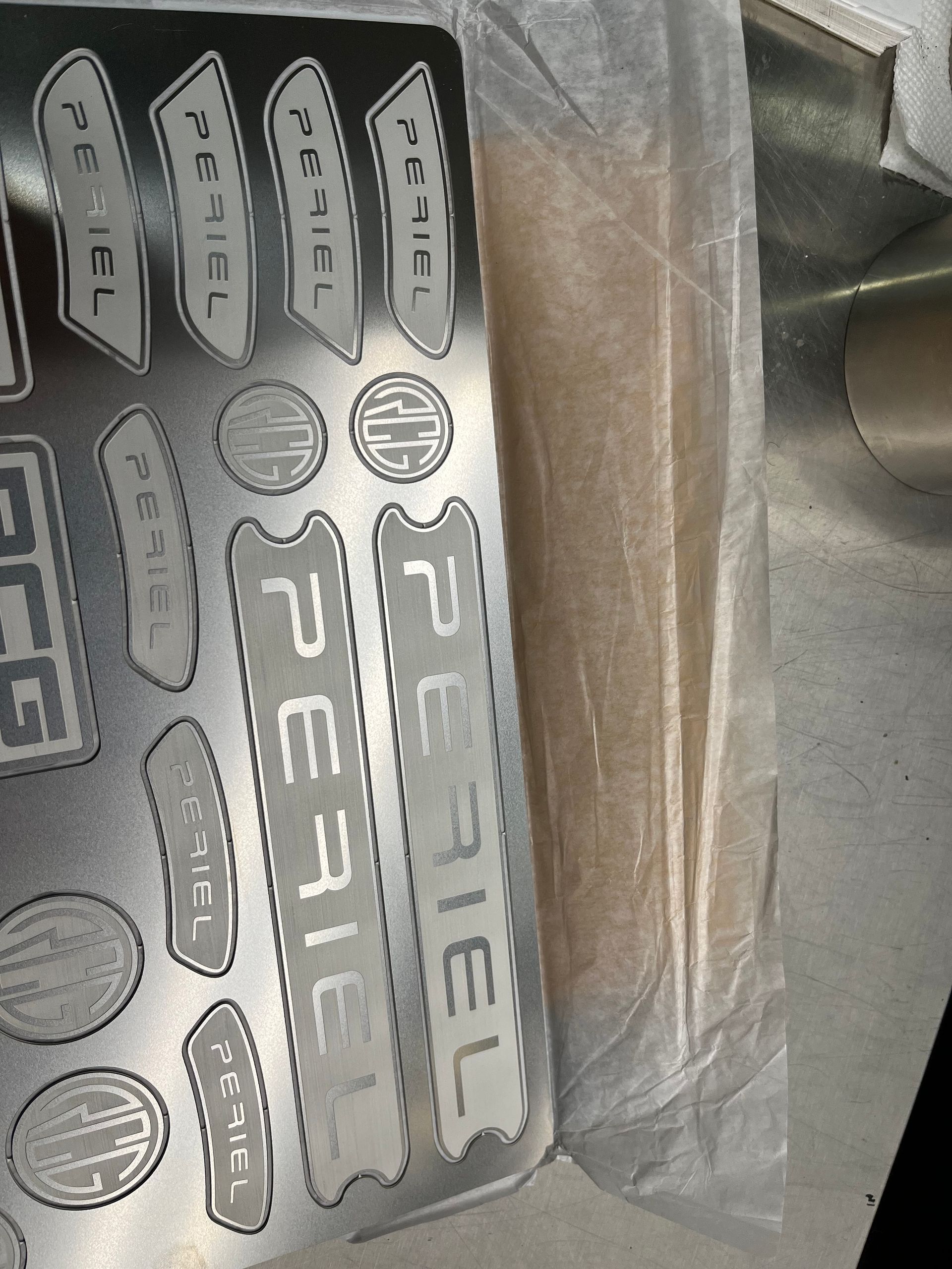 Silver sticker sheet with assorted black labels and logos inside a plastic package.