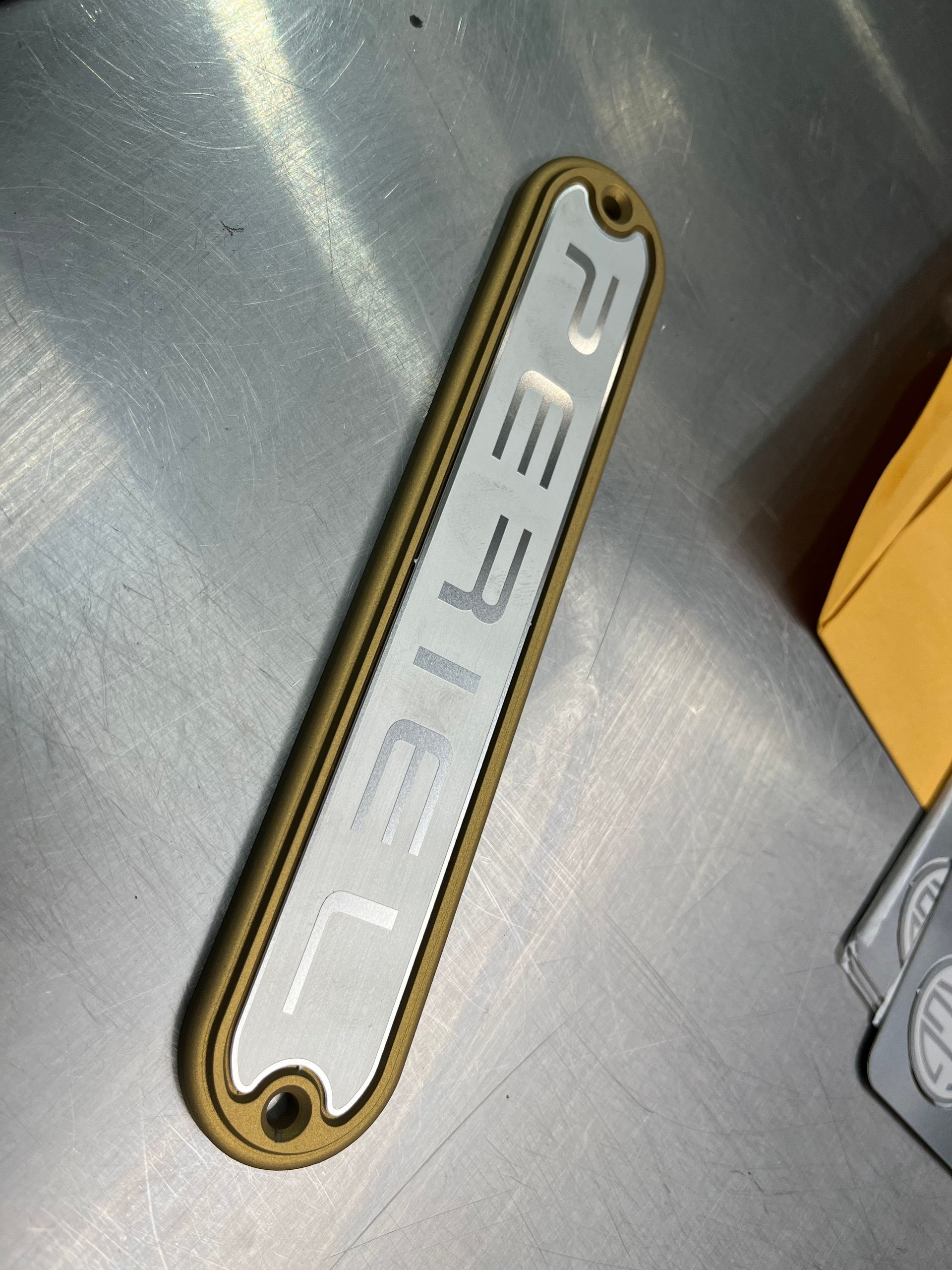 Gold metal nameplate with cutout letters on a gray surface