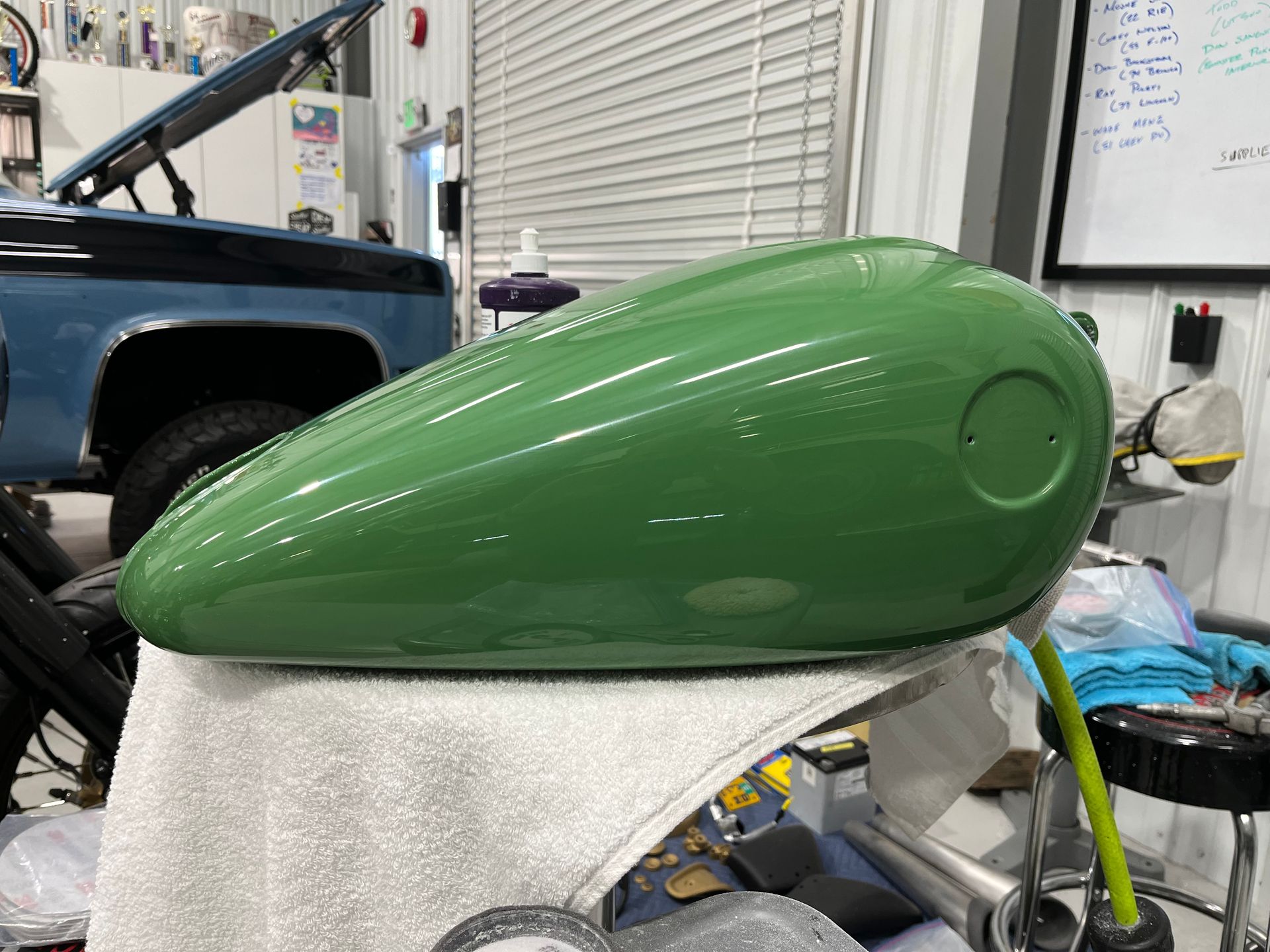 Green motorcycle fuel tank on a workbench in a garage workshop