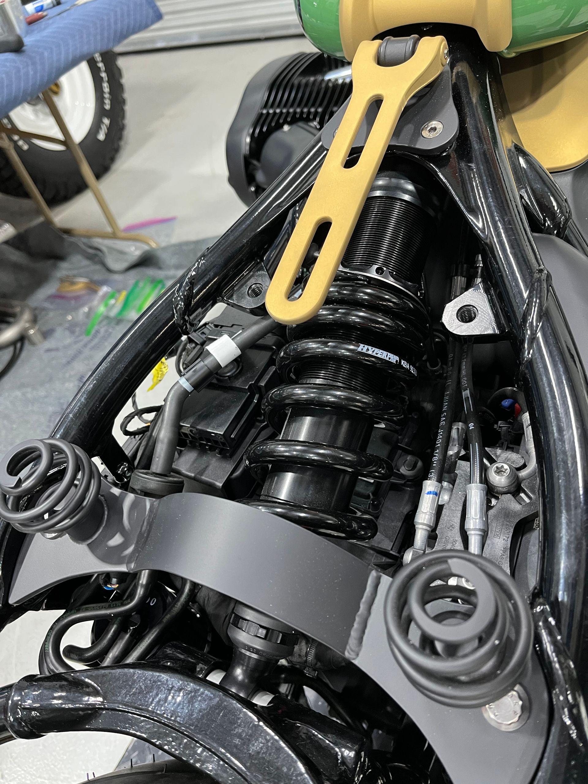Close-up of a motorcycle engine bay with black frame, exposed wiring, and suspension parts.