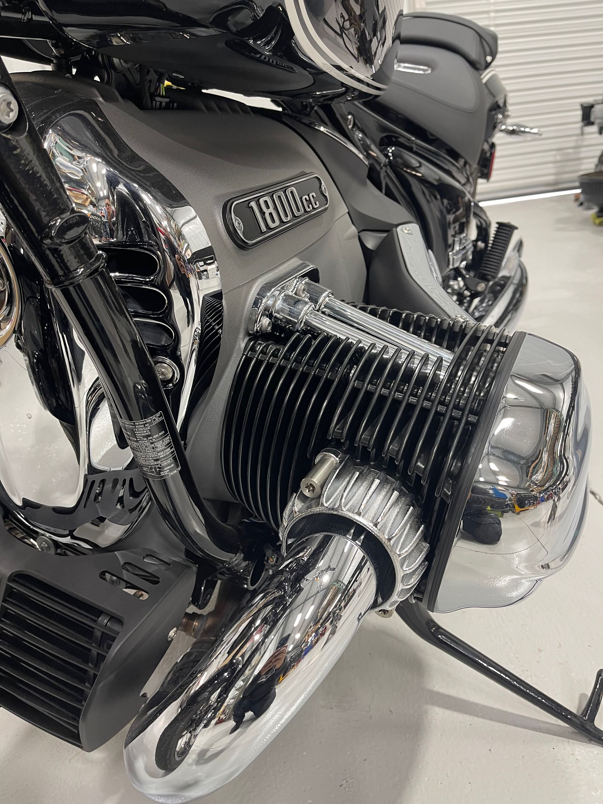 Chrome motorcycle engine and exhaust on a black bike in a garage