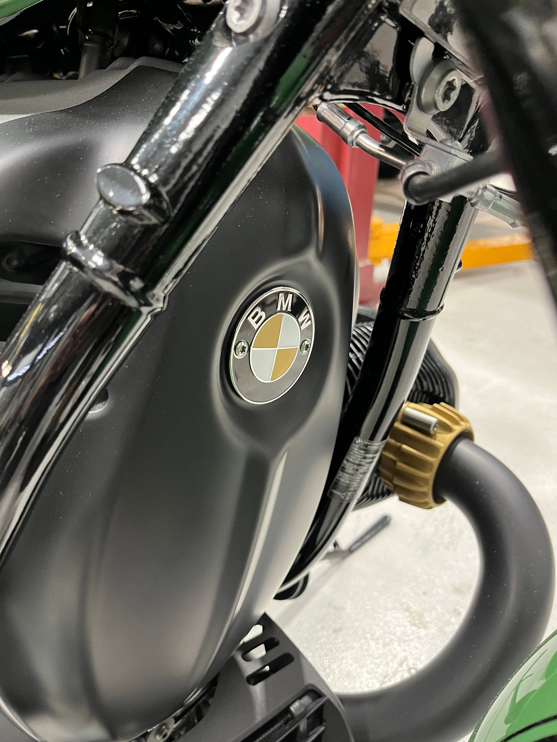 Close-up of a black motorcycle fuel tank and frame with a gold engine part.