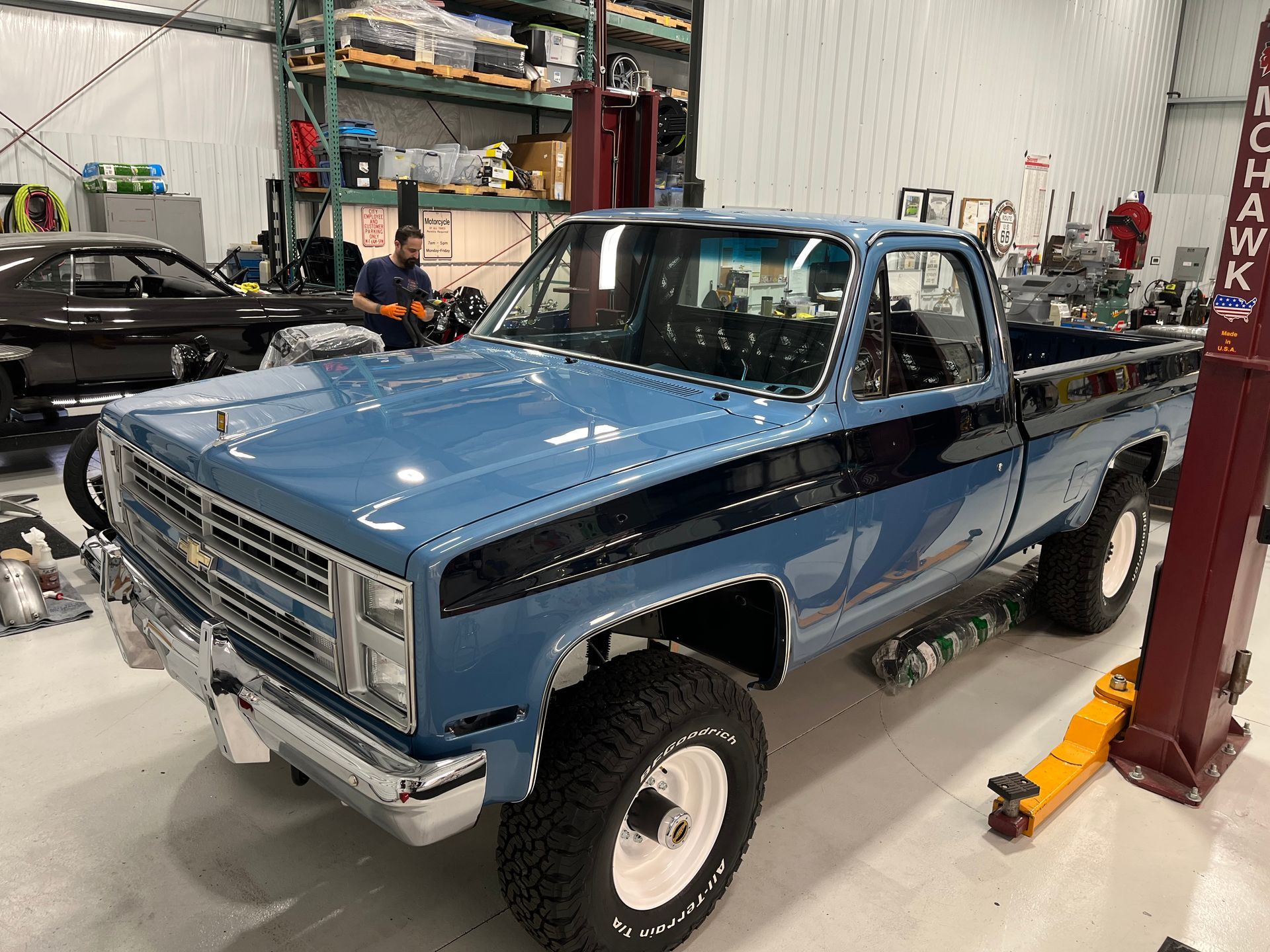 Blue classic pickup truck in a workshop beside a vehicle lift