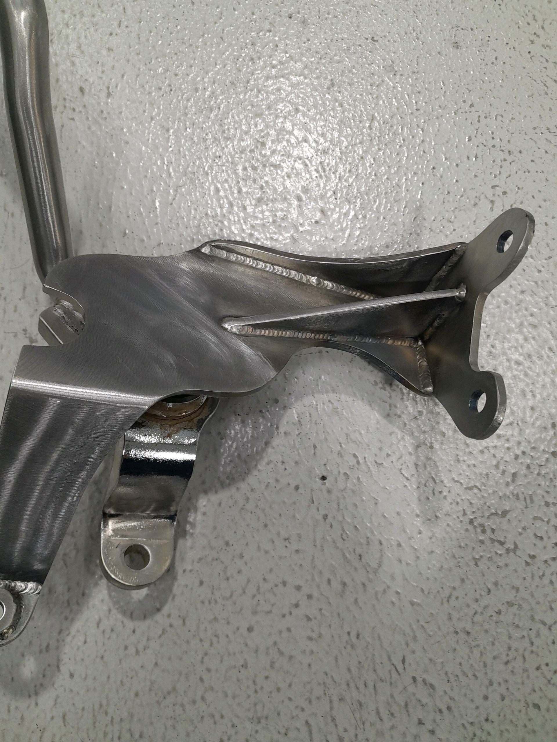 Bent metal bracket with torn gray strap on a textured gray floor