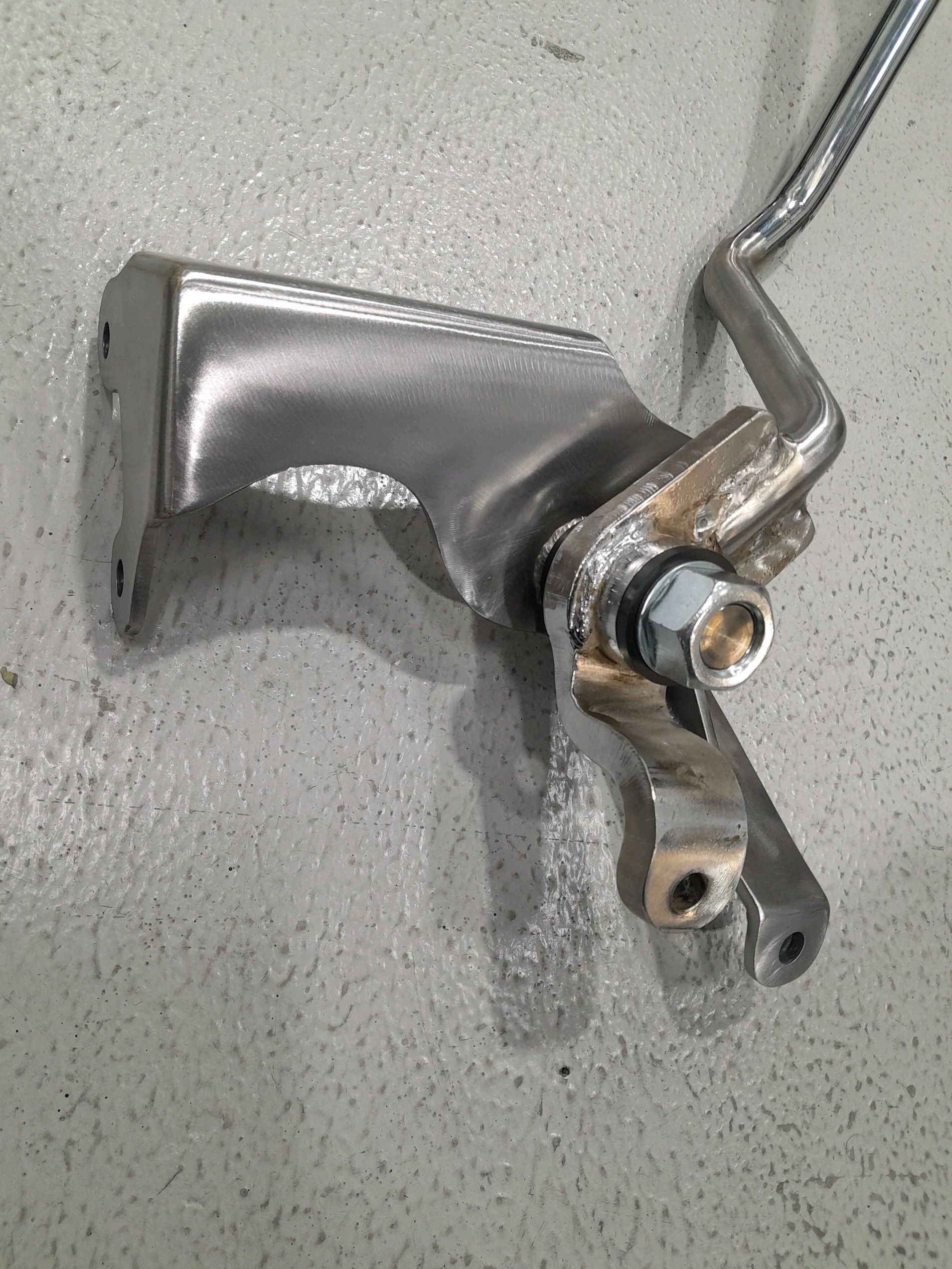 Bent metal car door handle and mounting bracket on a gray surface