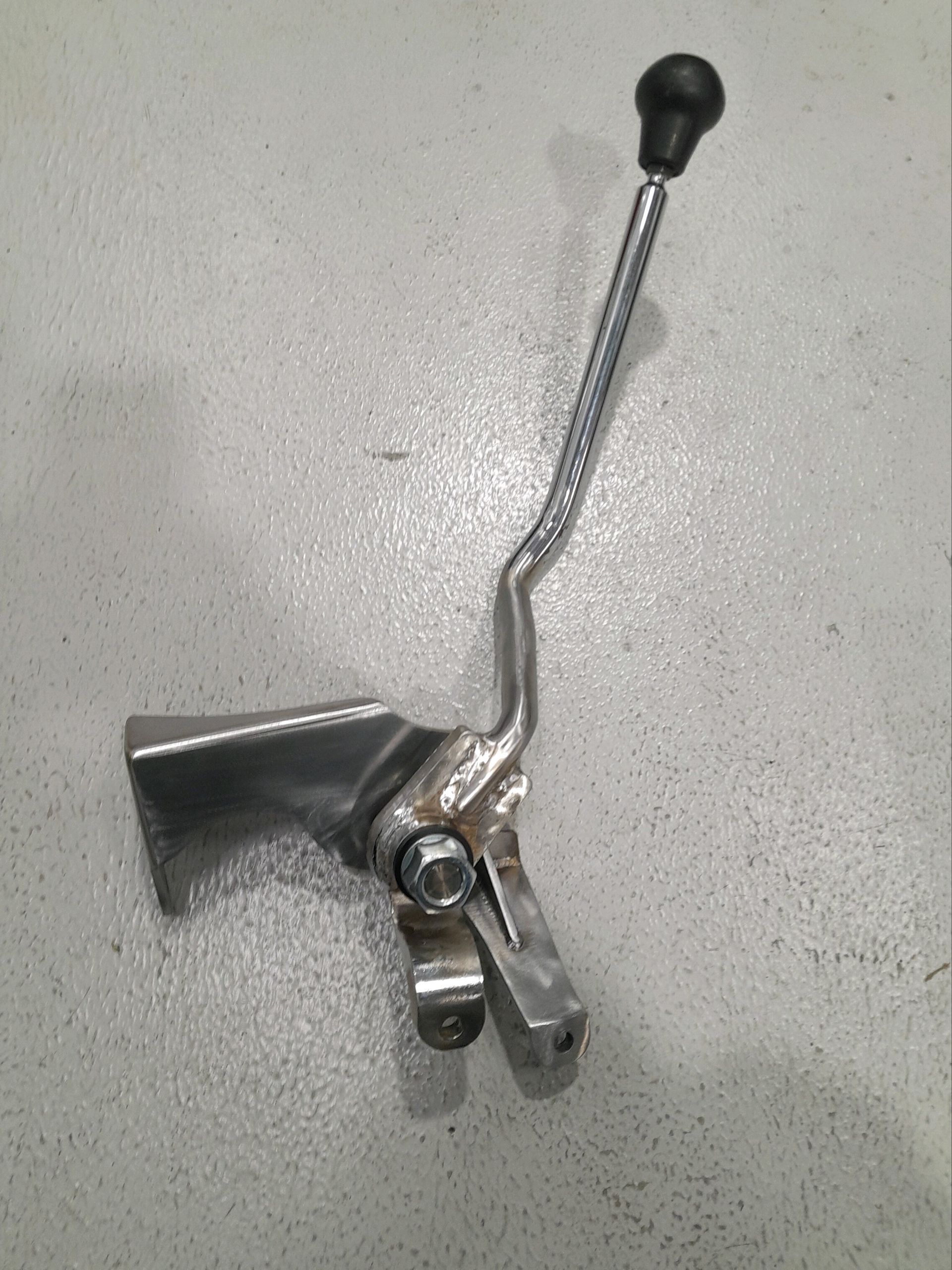 Metal lever handle with black knob and silver bracket on a light gray surface