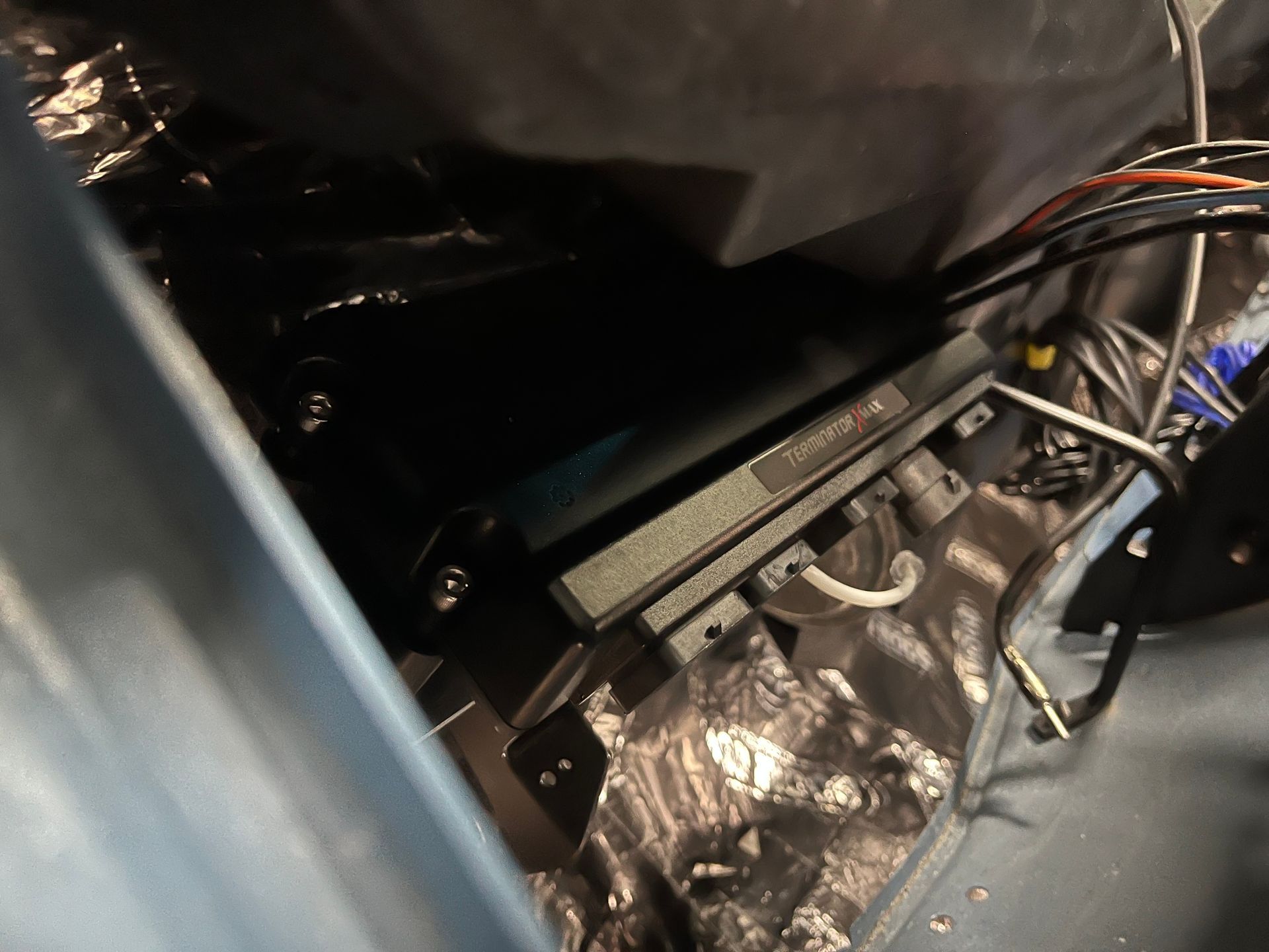 Close-up of exposed car interior wiring and components under a seat, with silver insulation foil.