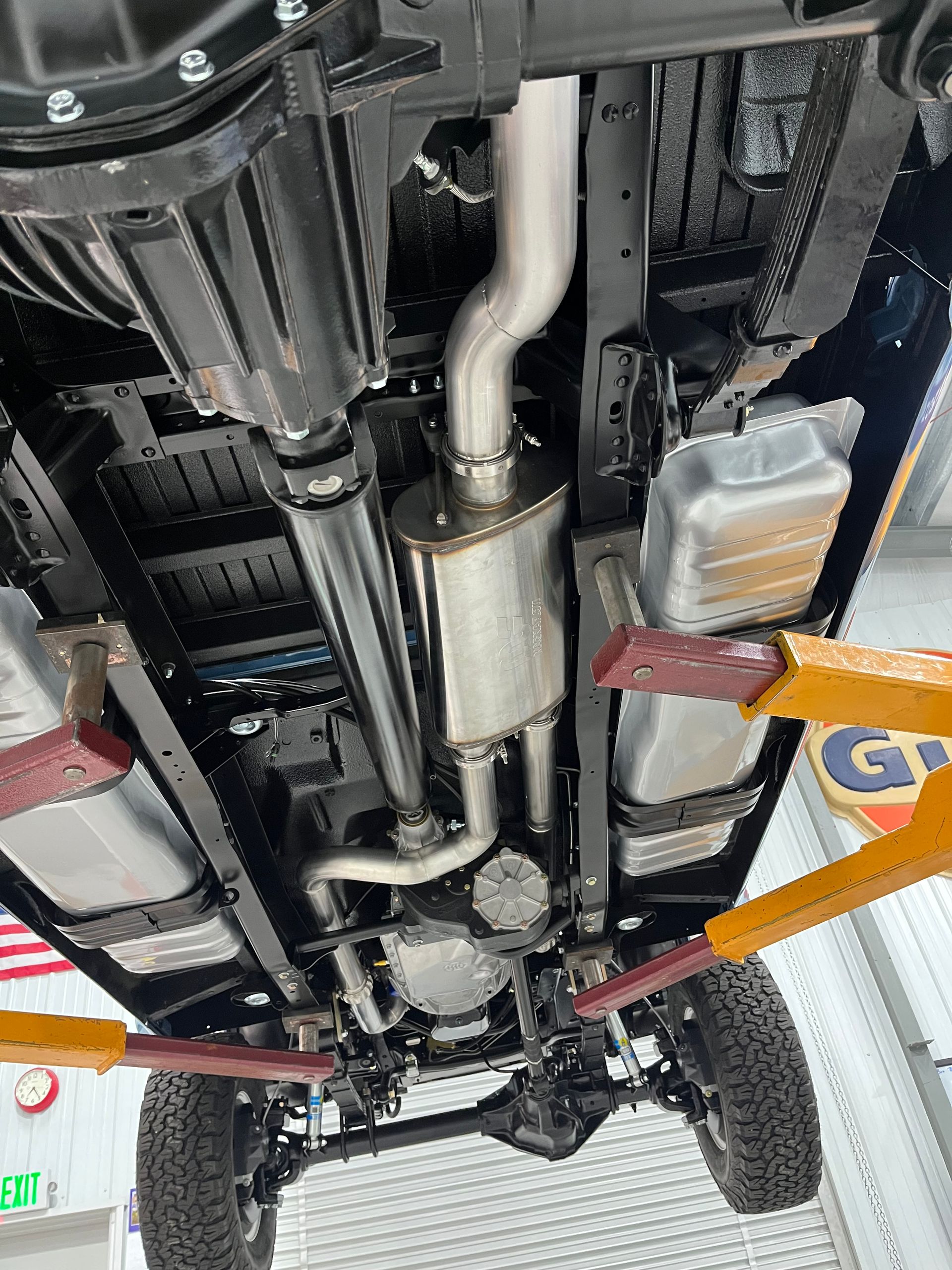 Undercarriage of a vehicle on a lift, showing exhaust, suspension, and frame components.