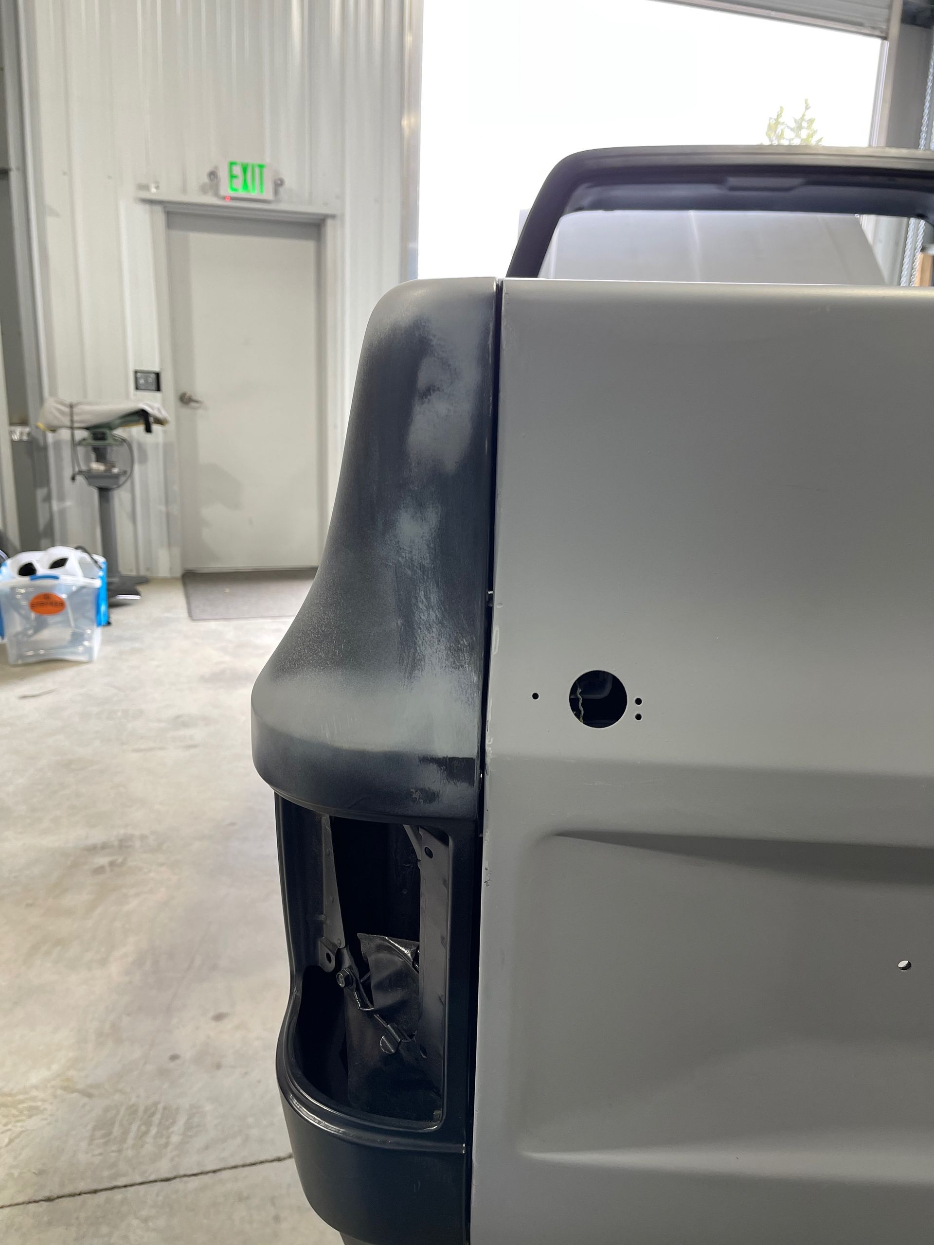 Damaged white truck rear corner with missing taillight in an indoor garage