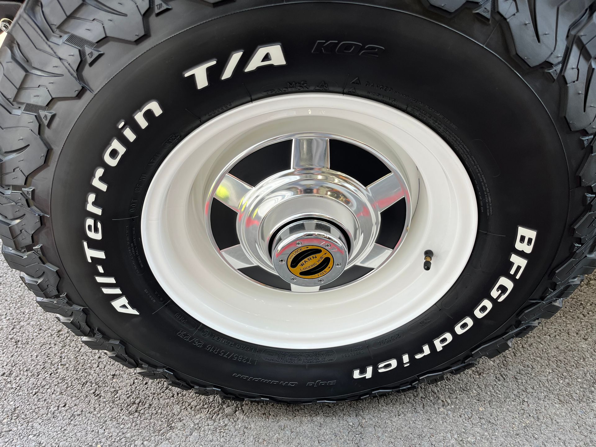 Close-up of a truck wheel with white steel rim and black All-Terrain T/A BFGoodrich tire.