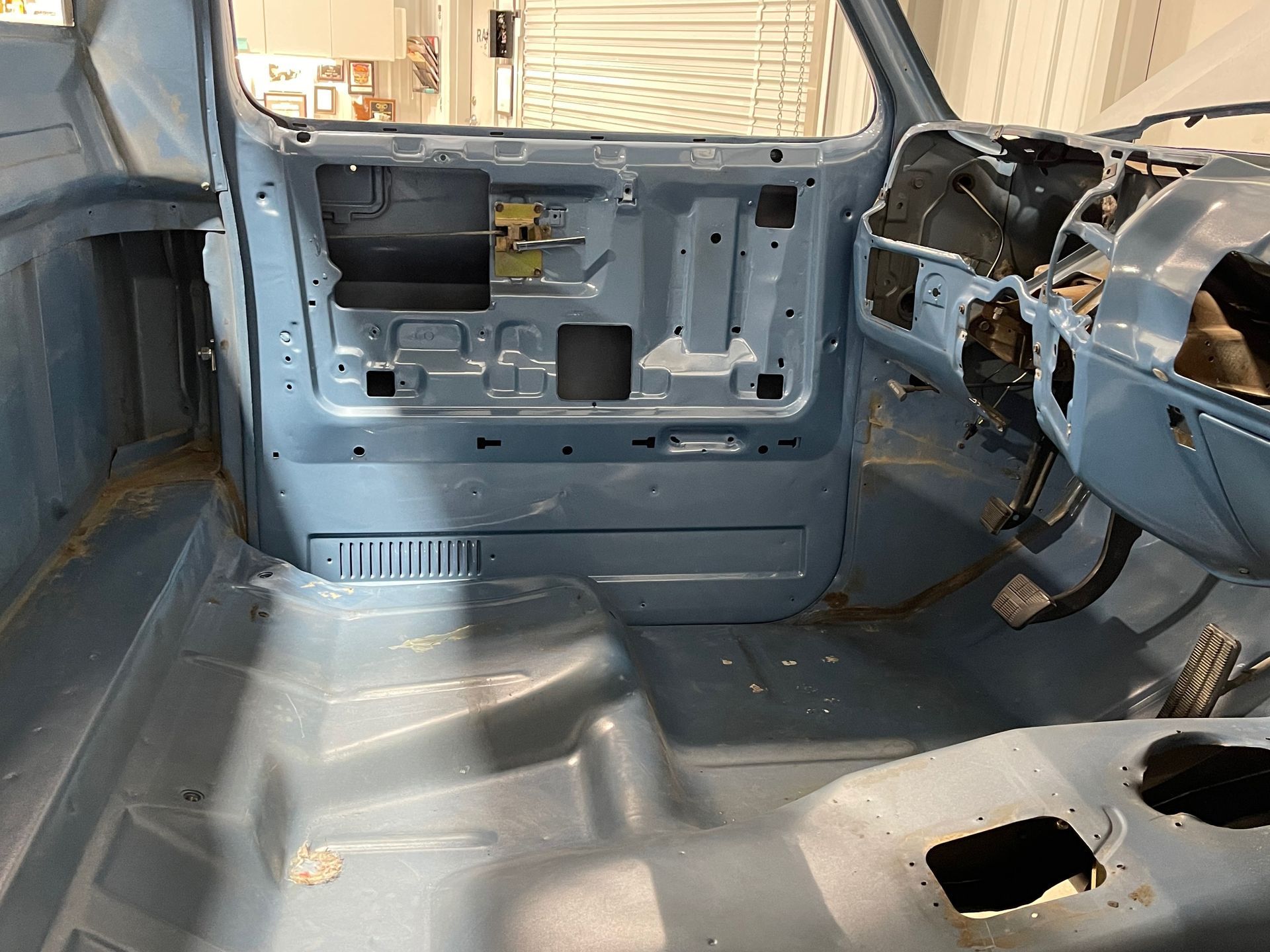 Empty stripped car interior with blue-gray floor, missing dashboard and open side panels