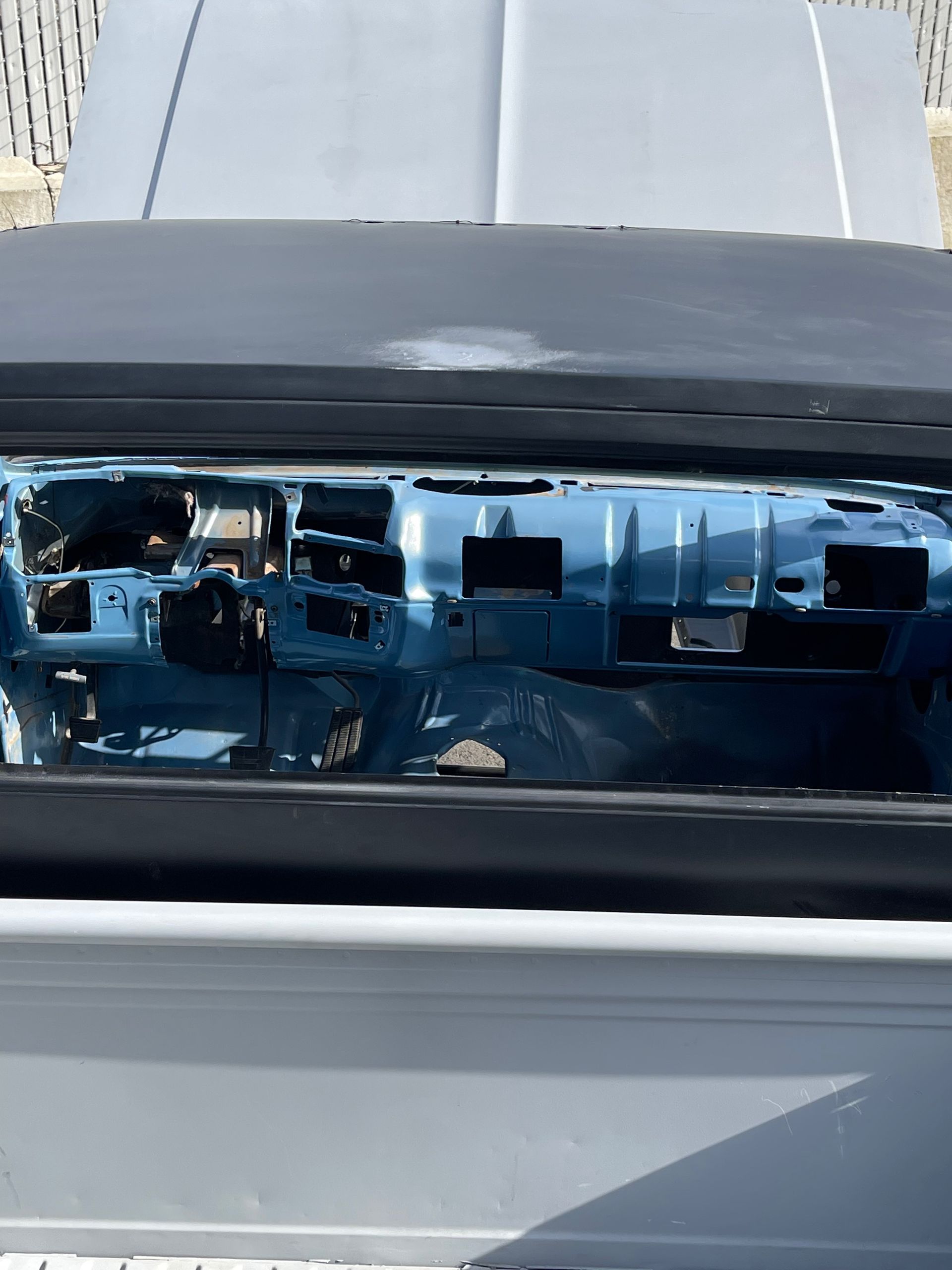 Damaged blue car headlight with exposed internal wiring and broken lens on a white vehicle front