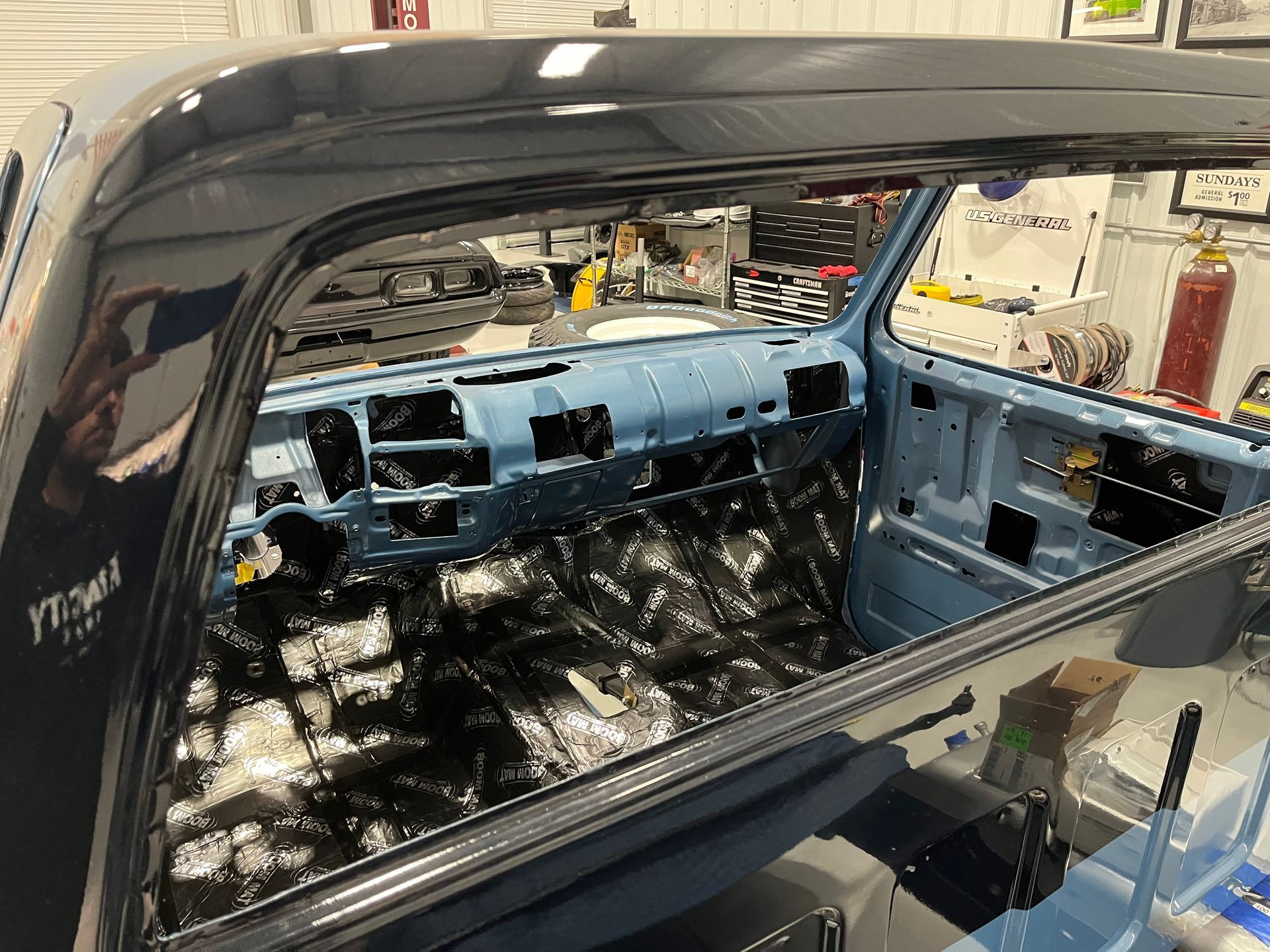 Car interior stripped for restoration, with exposed blue metal and no seats.