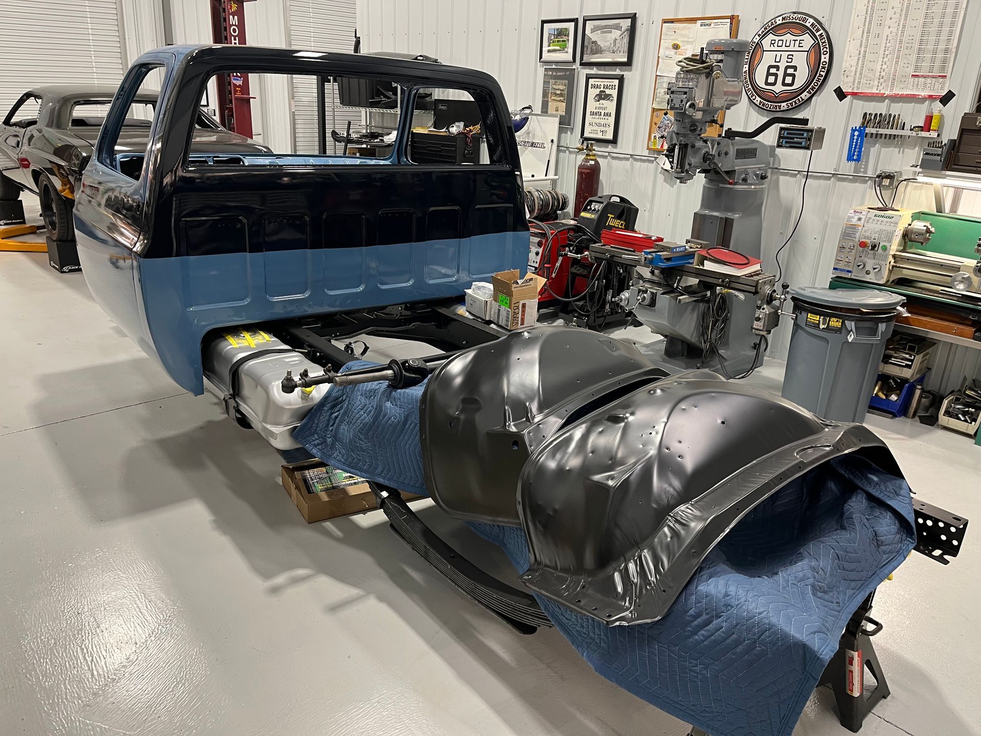 Partially assembled blue and black vehicle body in an auto repair workshop