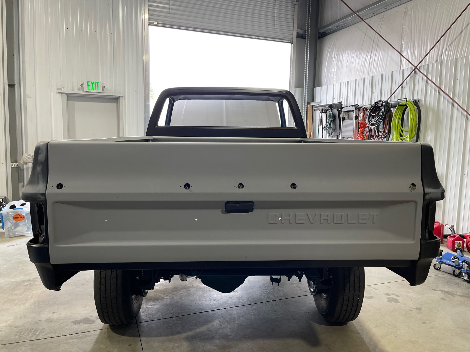 Rear view of a light gray pickup truck inside a warehouse garage