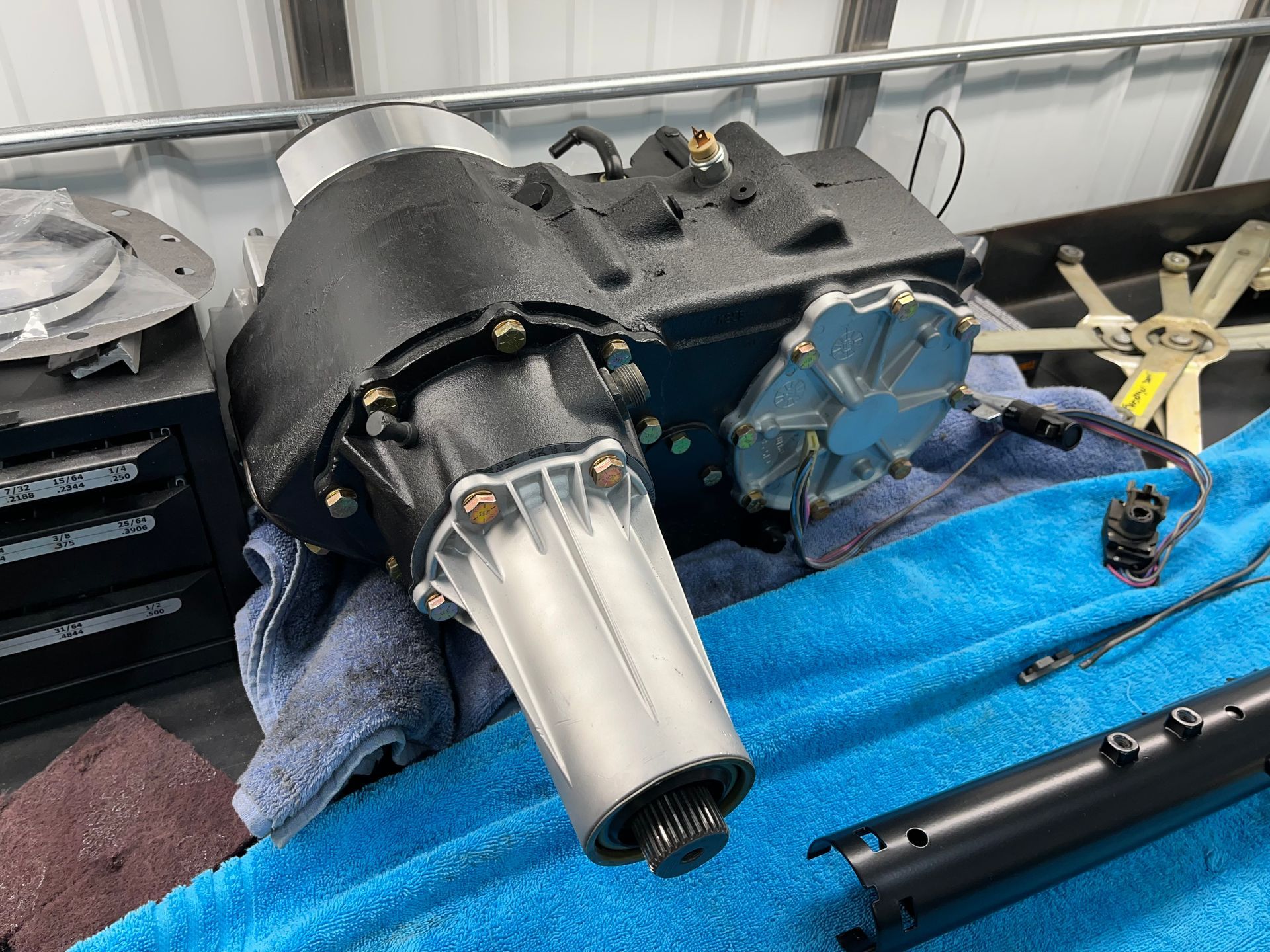 Metal automotive part with a silver cone and black housing on a blue towel in a workshop