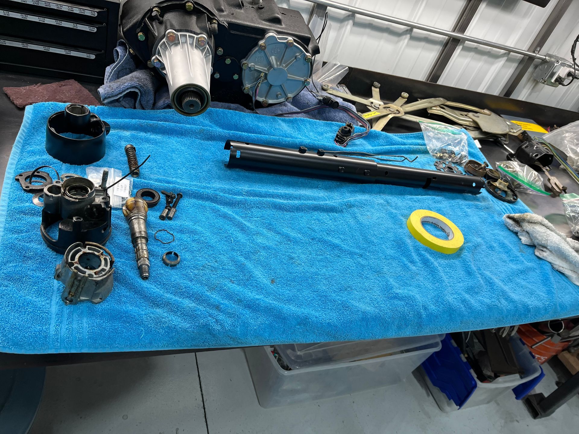 Disassembled metal parts and tools laid out on a blue towel on a workbench