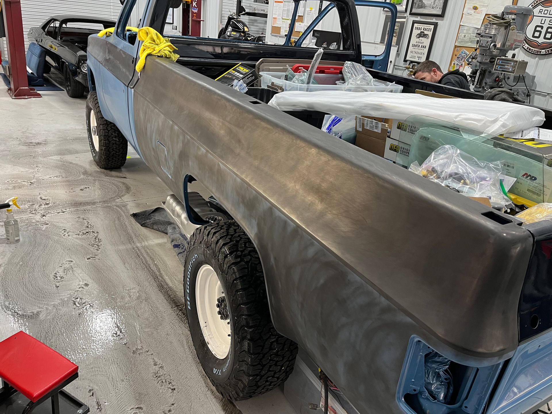 Damaged gray pickup truck in a garage, with tools and a yellow chain on the bed.
