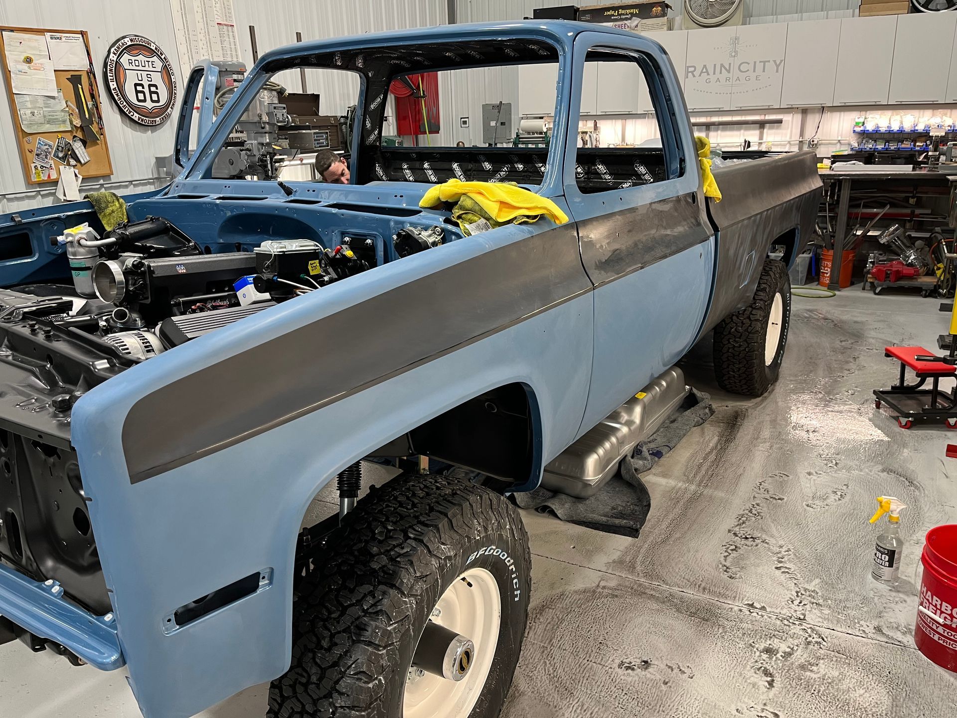Blue vintage pickup truck in a workshop, front end disassembled during restoration