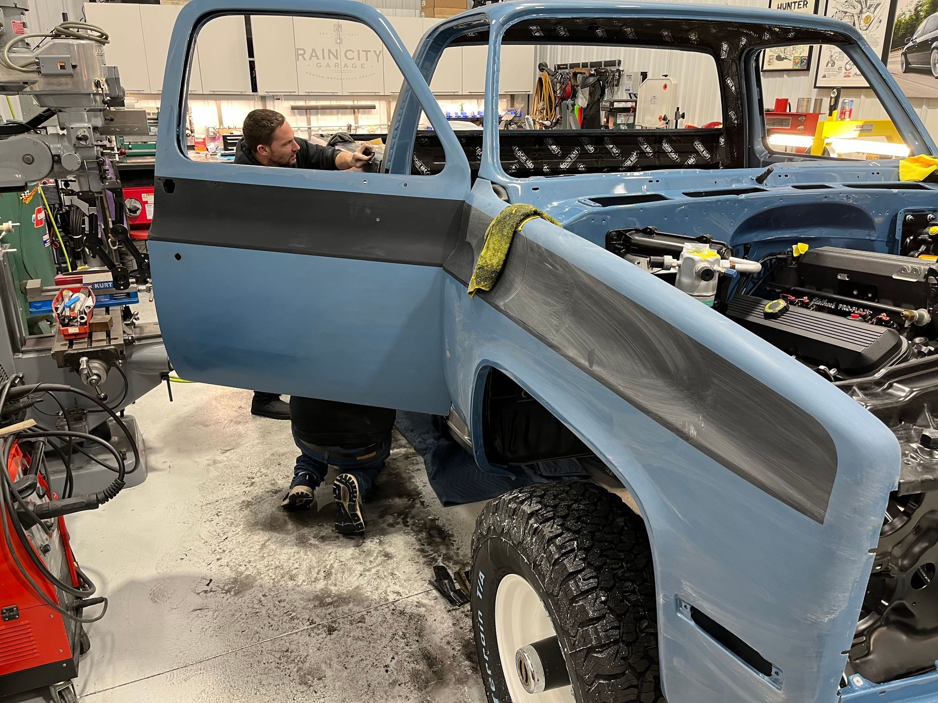 Vintage truck body being painted blue in an auto repair shop