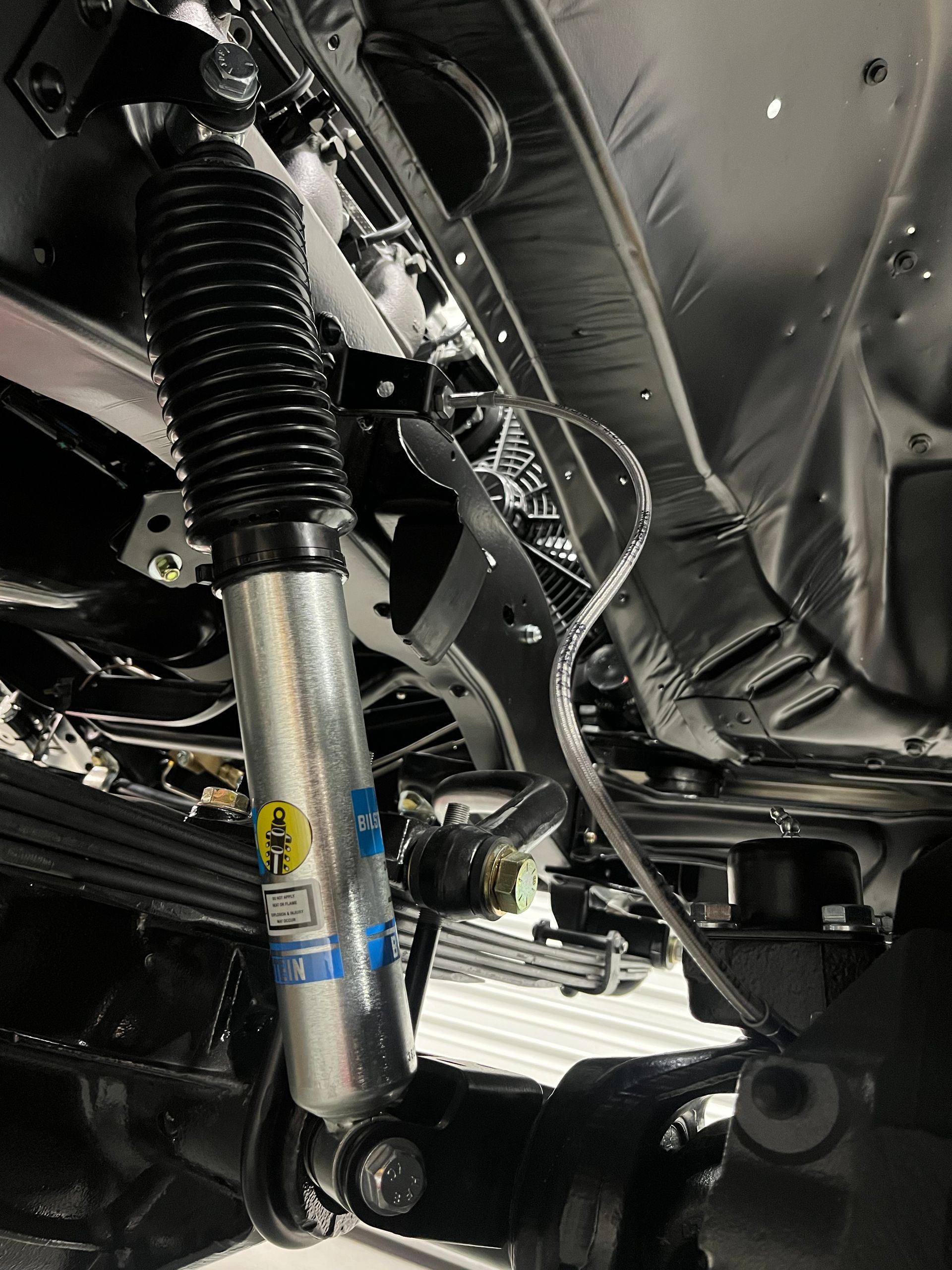 Close-up of a car suspension strut and undercarriage components in a garage