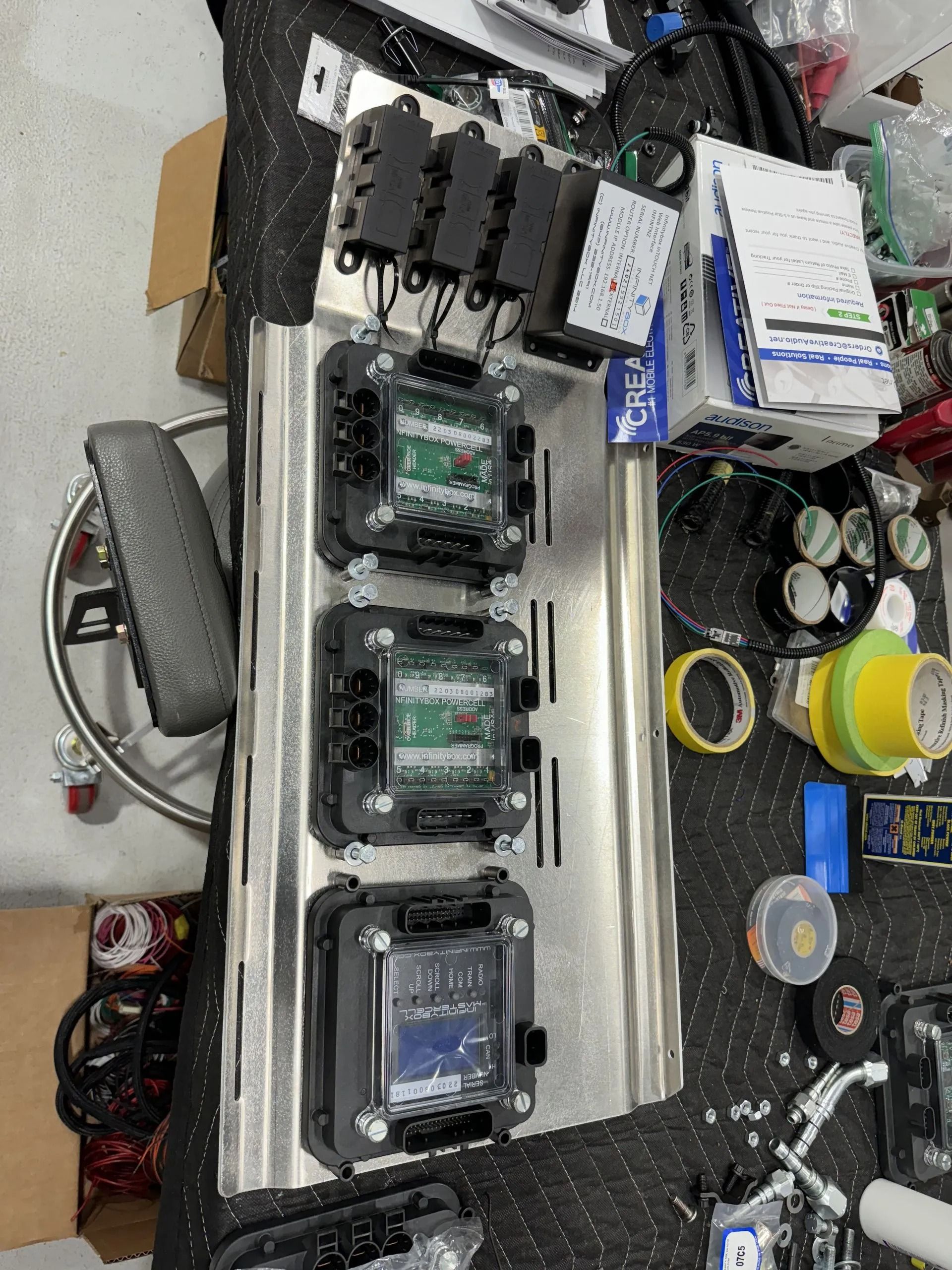 Workbench with electronic components, circuit boards, cables, and tools laid out in a cluttered repair area.