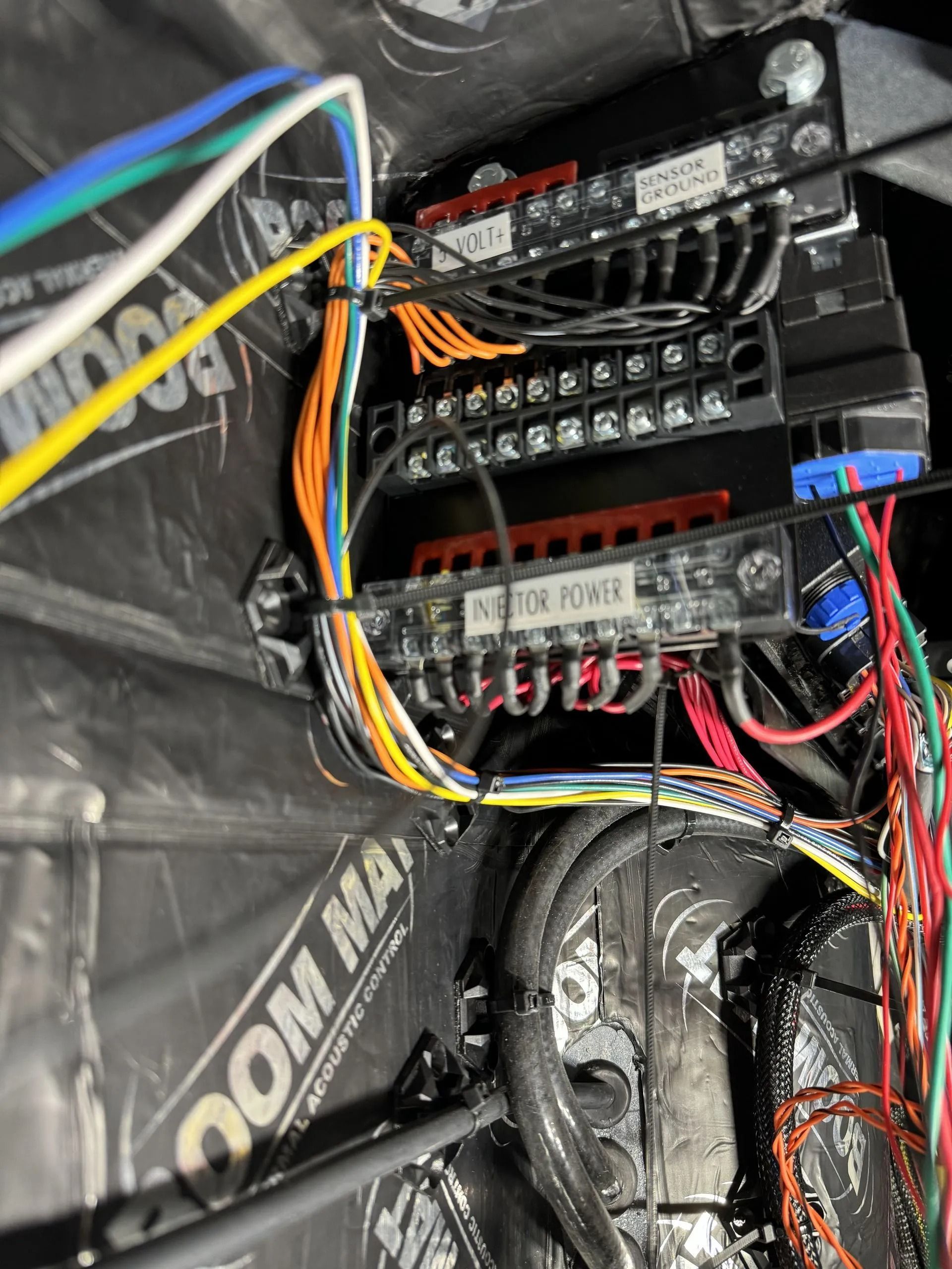 Close-up of a wired electronic control board with multicolored cables and screw terminals in a black enclosure