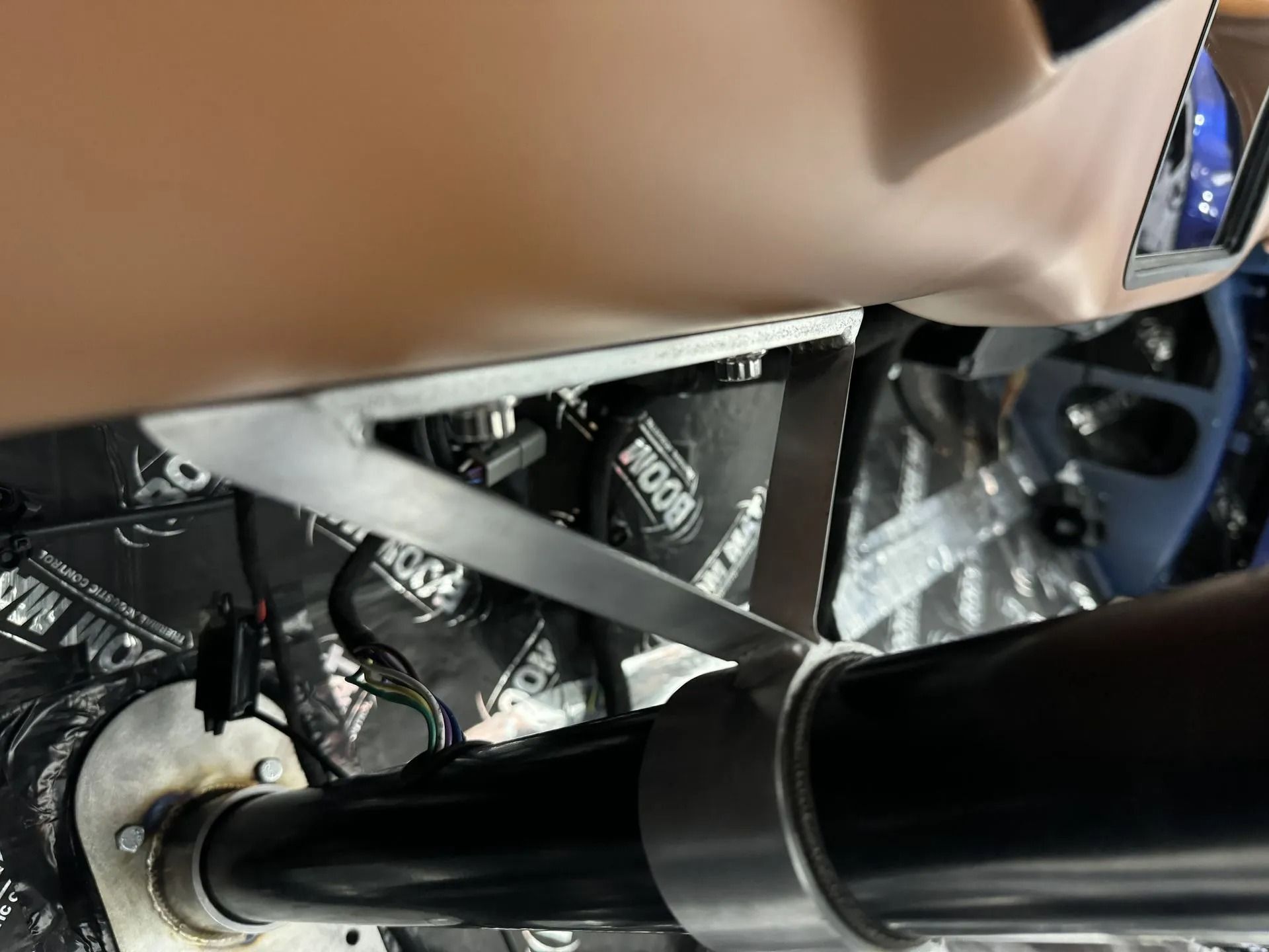 Close-up of a car’s metal chassis and suspension components near a black cylindrical rod