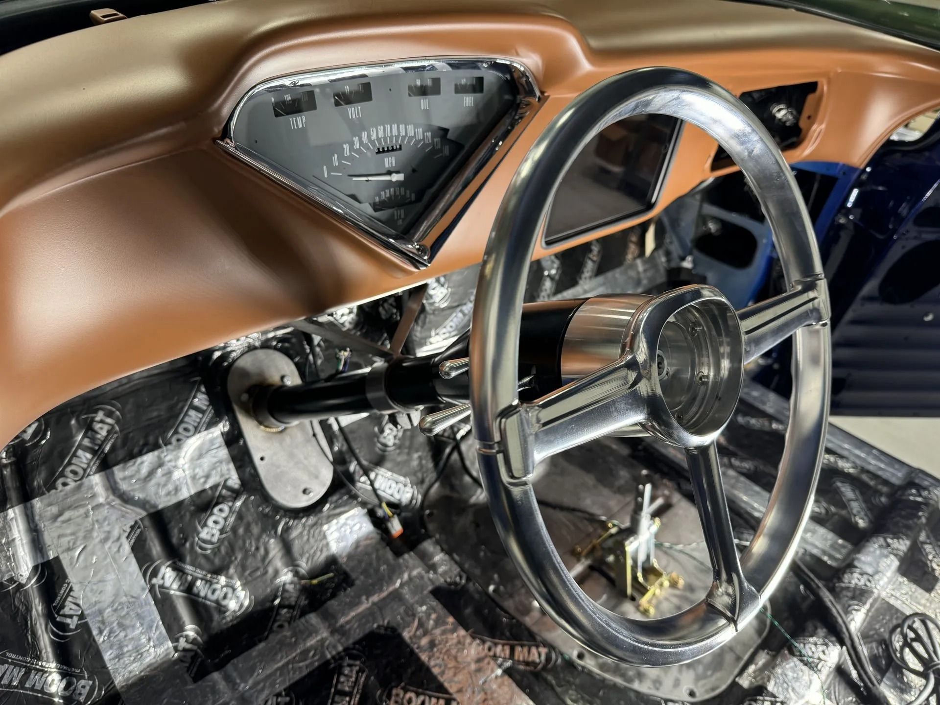 Vintage car interior with copper dashboard, chrome steering wheel, and metallic floor panels