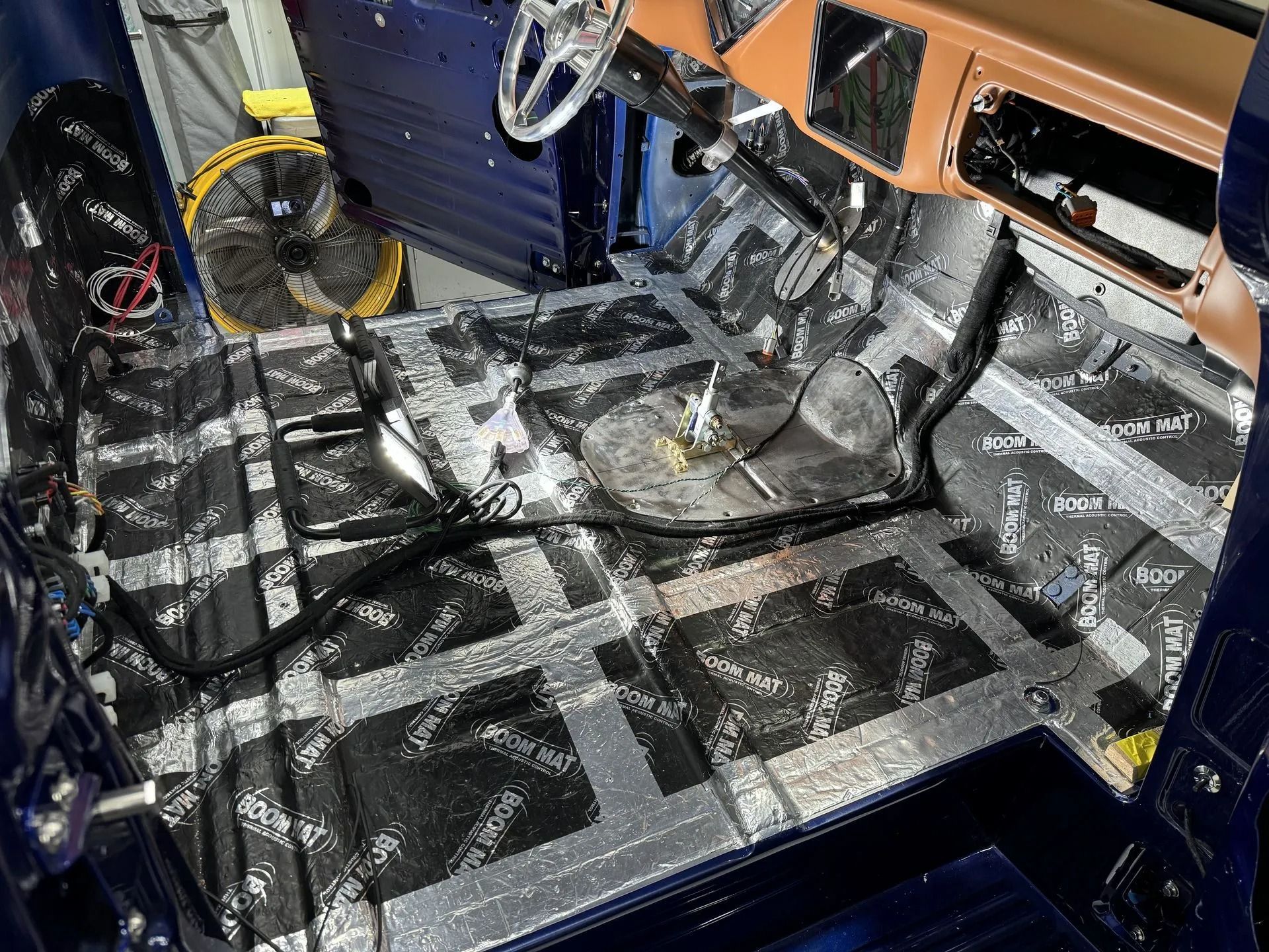 Stripped car interior with exposed metal floor, wiring, and dashboard during restoration