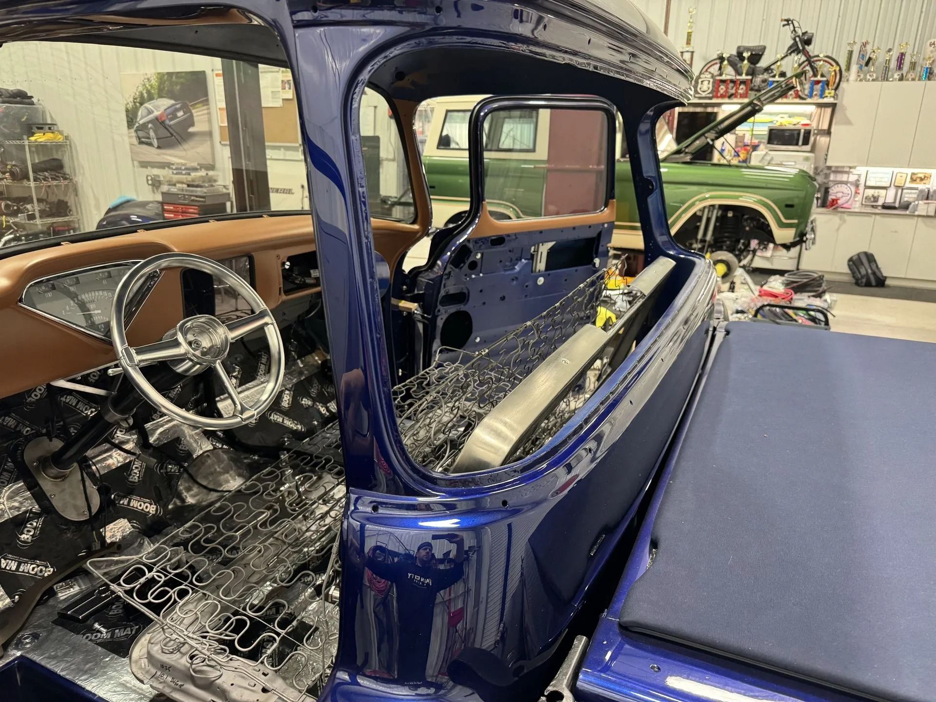 Blue classic car interior during restoration in a workshop, with stripped metal and exposed frame.