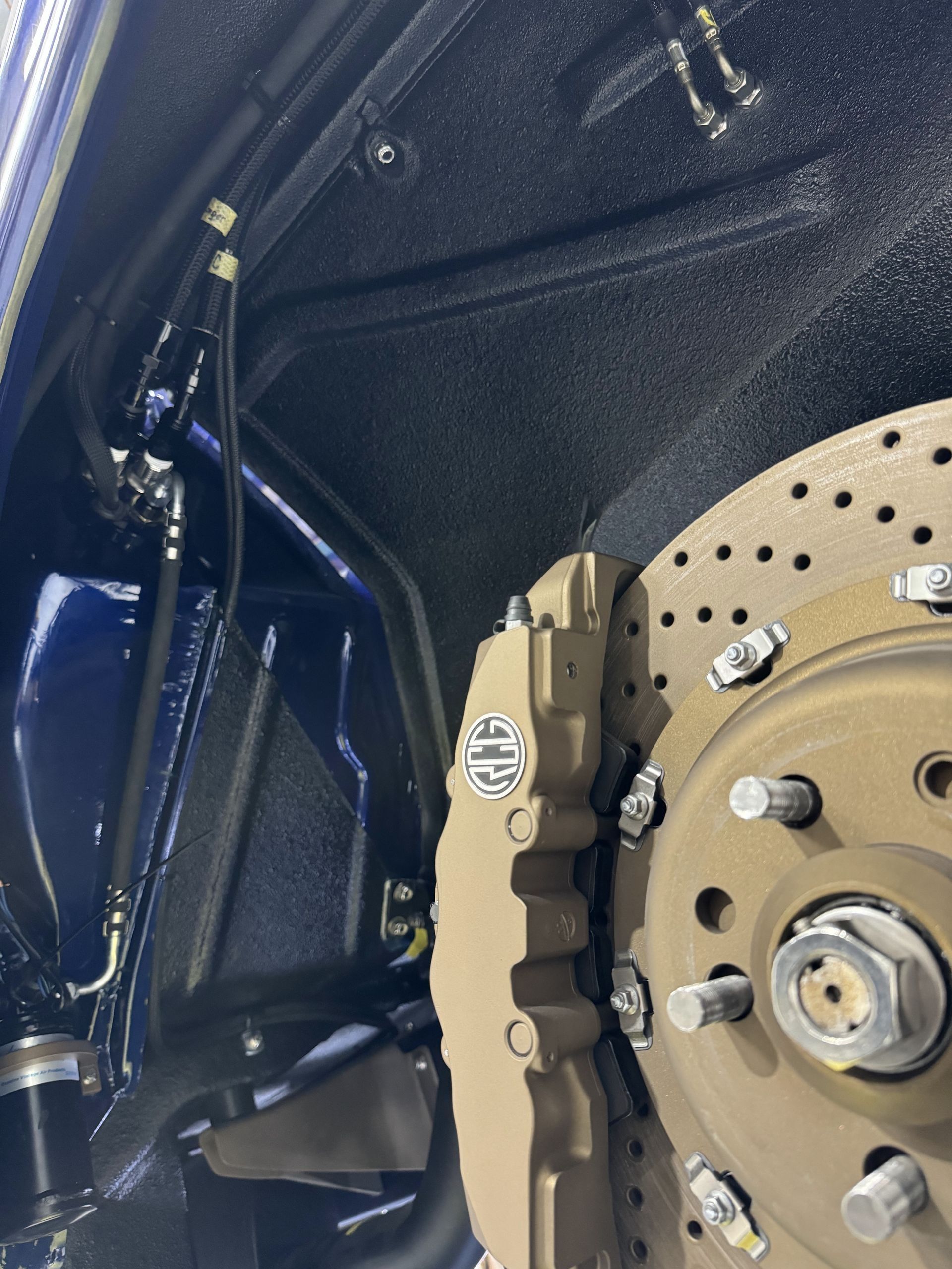 Close-up of a car brake rotor and caliper inside a dark wheel well.