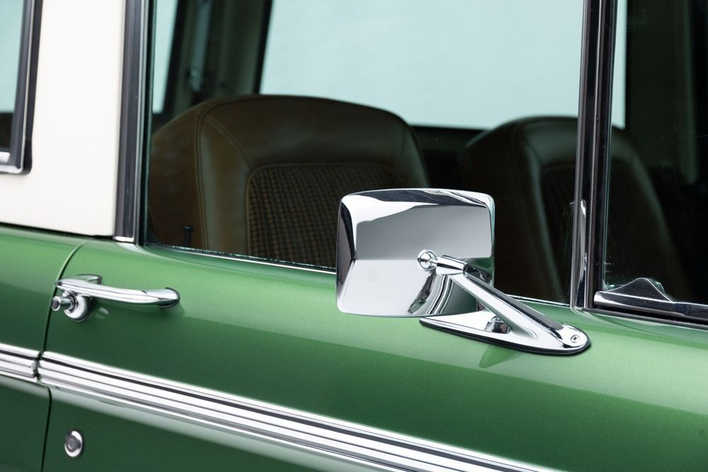 Green classic car door with chrome side mirror and trim
