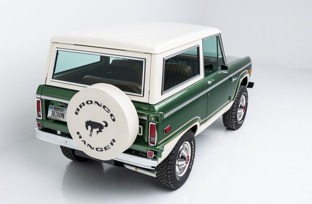Green classic SUV with a white roof and spare tire, shown from the rear on a white background