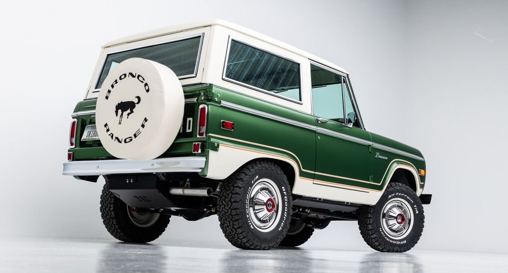 Green vintage off-road SUV with white roof and spare tire on a studio backdrop