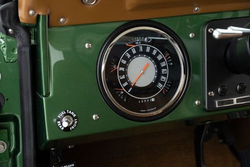 Close-up of a vintage vehicle dashboard with a green panel and a central round gauge.