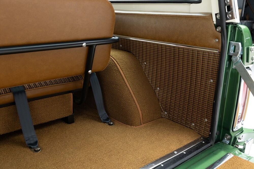 Car interior with brown woven upholstery and a green door frame, showing rear seat area and floor mats