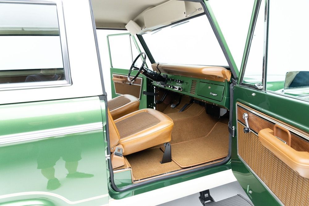 Green vintage car interior with open door, tan seats, and dashboard visible