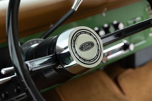 Close-up of a vintage Ford steering wheel and dashboard inside a classic car.