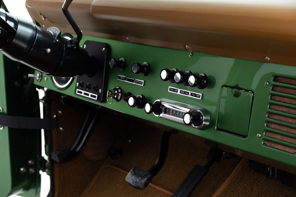 Control panel with switches and dials on a green console inside a vehicle cabin