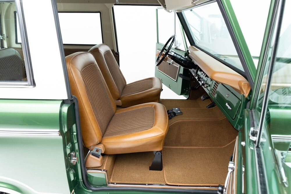 Green vintage car interior with brown front seats and open passenger door