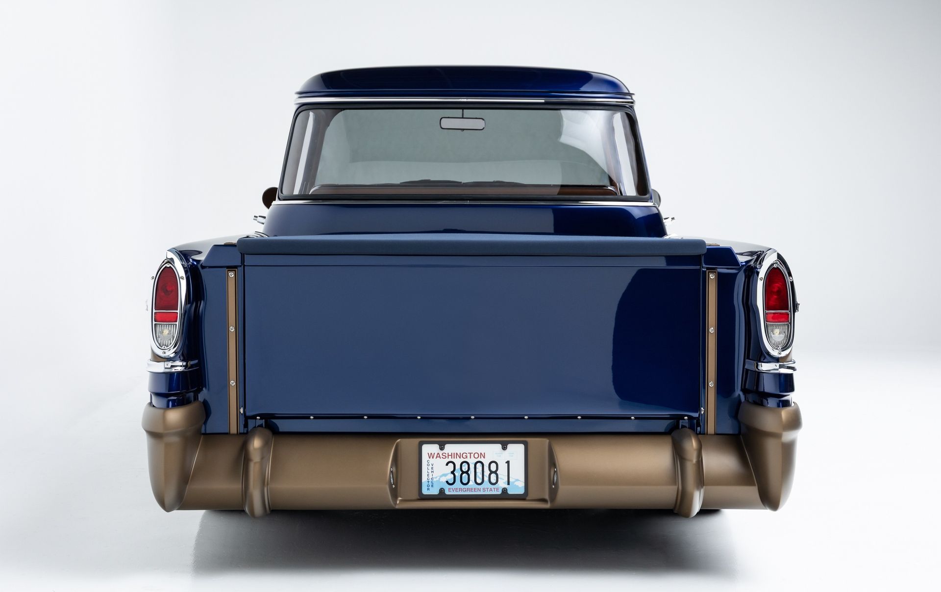 Rear view of a blue vintage pickup truck with tan lower body on a white background