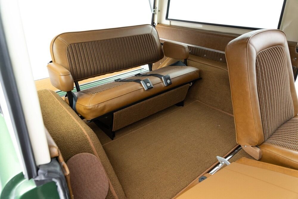 Brown upholstered bus bench seats inside a vehicle cabin with a window and aisle visible