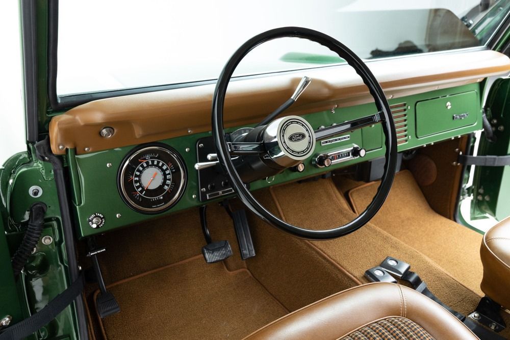 Vintage car interior with green dashboard, tan trim, and large steering wheel