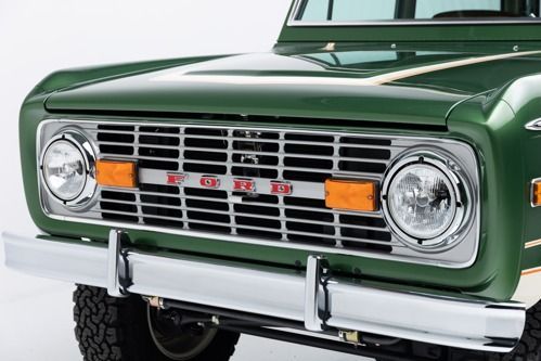 Front view of a green vintage truck with chrome grille and bumper, orange lights, and round headlights