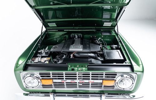 Green classic car with hood open, showing the engine bay and front grille.