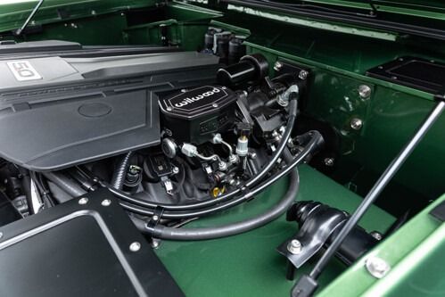 Open car engine bay with black components and green body panels