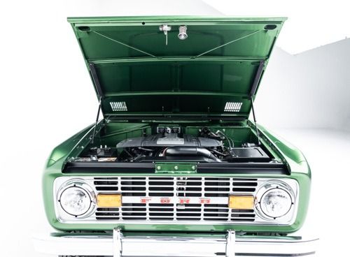 Green classic car with hood open, showing its engine and front grille