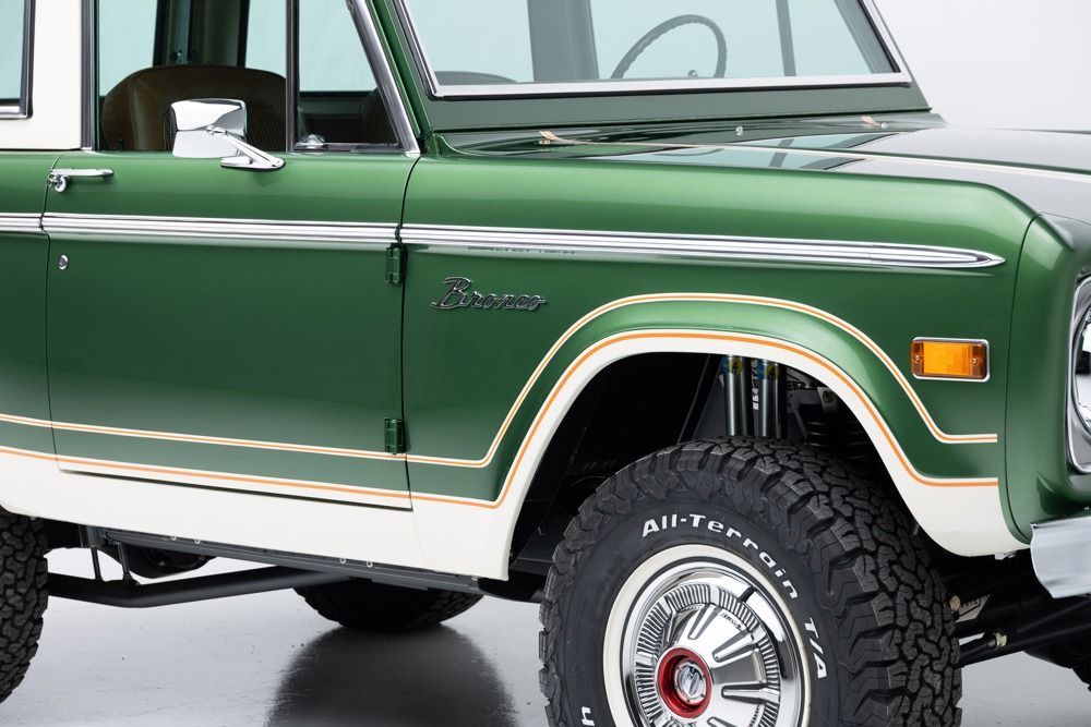 Green vintage SUV with white top and off-road tires, shown in side view
