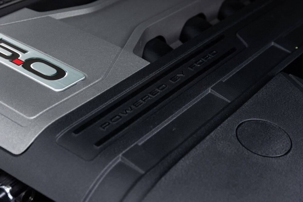 Close-up of a car engine cover with a silver 3.0 badge and black plastic trim